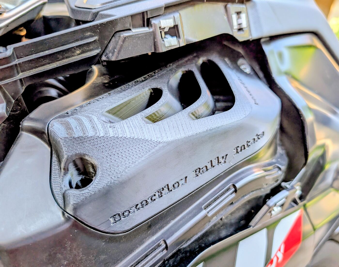 Close-up of a BoxerFlow Rally Intake cover fitted to a BMW R 1300 GS airbox, showing the three open flow channels and the engraved BoxerFlow Rally Intake lettering.